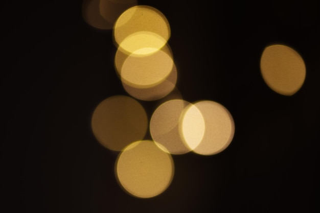 Goldene abstrakte Bokeh-Lichter auf schwarzem Hintergrund Feiertagshintergrund für Design