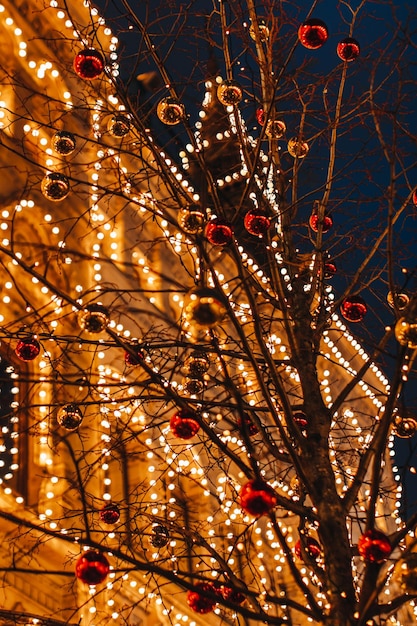 Goldene Baumzweige, die mit Weihnachtsbällen in festlicher Abendatmosphäre geschmückt sind