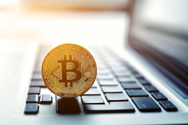 Goldene Bitcoin-Münze auf der Laptop-Tastatur. Handelskonzept