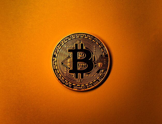 Goldene Bitcoin-Münze auf gelbem monochromem Hintergrund