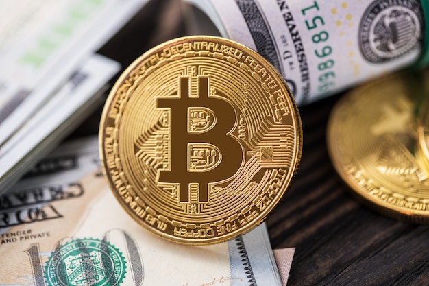 Goldene Bitcoin-Münze auf US-Dollar hautnah. Elektronische Kryptowährung