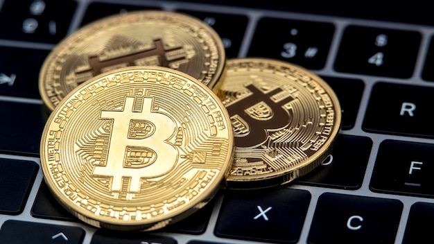 Goldene Bitcoin-Währung des physischen Metalls auf Notebook-Computertastatur. Weltweites virtuelles Internetgeld. Digitaler Münz-Cyberspace, Kryptowährung Gold BTC. Gute Investition zukünftige Online-Zahlung