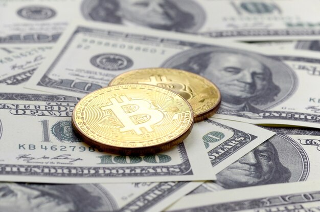 Goldene Bitcoins liegen auf vielen Dollarscheinen