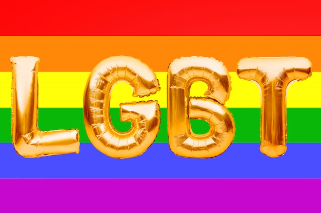 Goldene Buchstaben gemacht von Luftballons, die Wort LGBT auf Stolzregenbogenfahnenhintergrund bilden