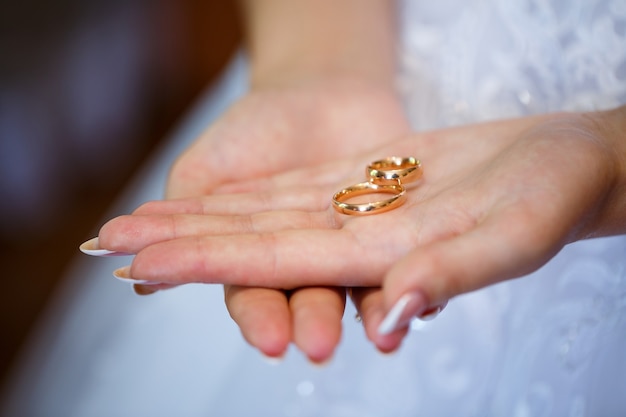 Goldene Eheringe in den Händen von Brautpaaren am Hochzeitstag