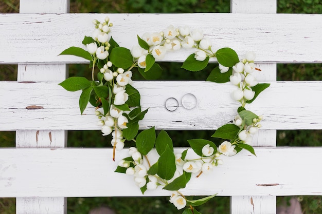 Goldene Eheringe mit Diamanten liegen innerhalb der Jasminblume im Brautblumenstrauß