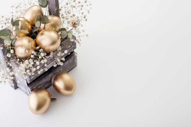 Goldene Eier mit Frühlingsblumen, mit Kopierraum. Das Konzept von Ostern.