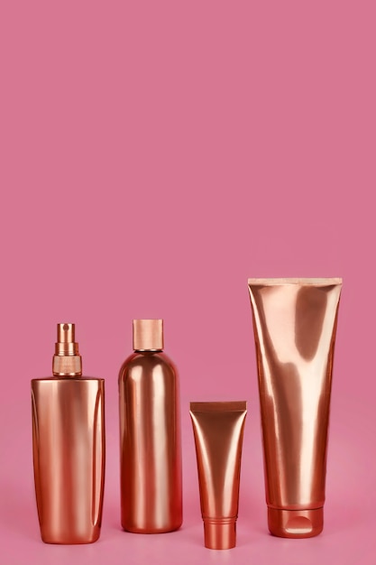 Goldene Flaschen, kosmetische Produkte auf rosa Oberfläche