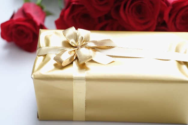 Goldene geschenkbox zum valentinstag mit roten rosenblüten