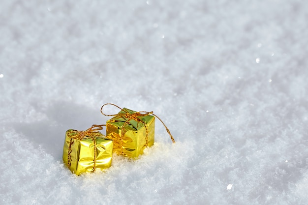 Goldene Geschenkboxen liegen auf Naturschnee