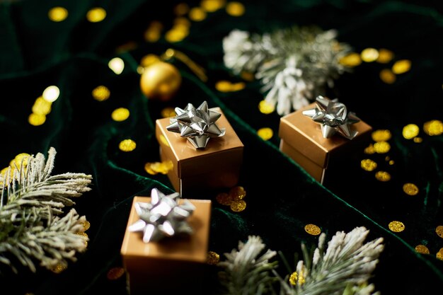 Goldene Geschenkboxen mit silbernem Band auf glänzendem velurgrünem Hintergrund mit Weihnachtsschmuck Flach liegend Kopieren Sie Platz Heiraten Sie Weihnachten