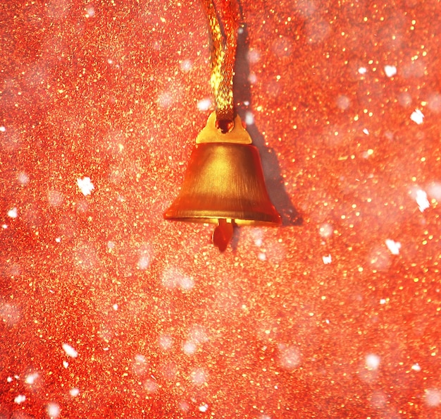 Goldene glocke auf dekorativem hintergrund des funkelns mit schneeeffekt.