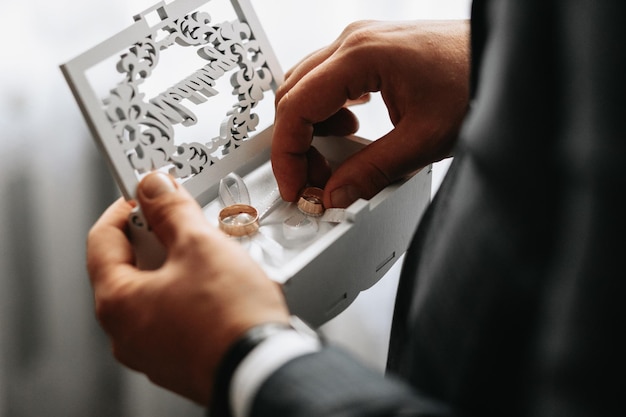 Foto goldene hochzeitsringe in einer geschenkbox in den händen des bräutigams in nahaufnahme