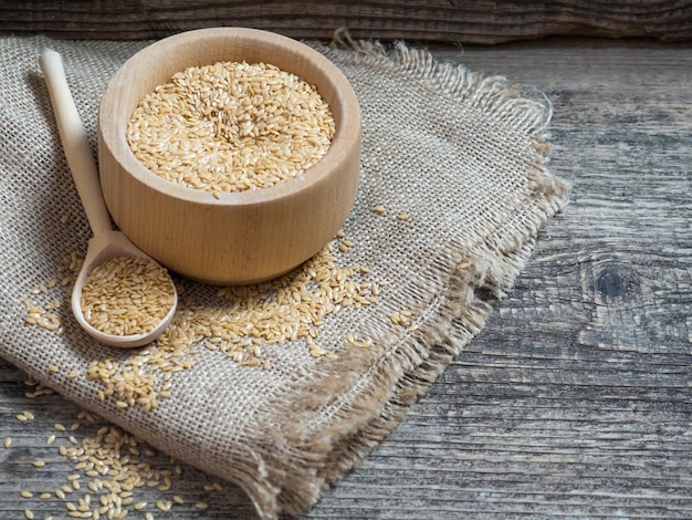 Goldene Leinsamen, Leinsamen in einem Holzlöffel auf einer alten rustikalen Hintergrundnahaufnahme, weißer Flachs