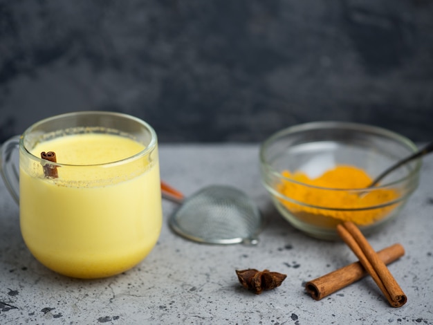 Goldene Milch der indischen Gewürzgelbwurz in einem Becher auf einer dunklen Steintabelle