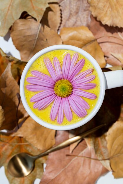 Goldene Milch in einer weißen Tasse, die mit einem rosa Gänseblümchen verziert ist