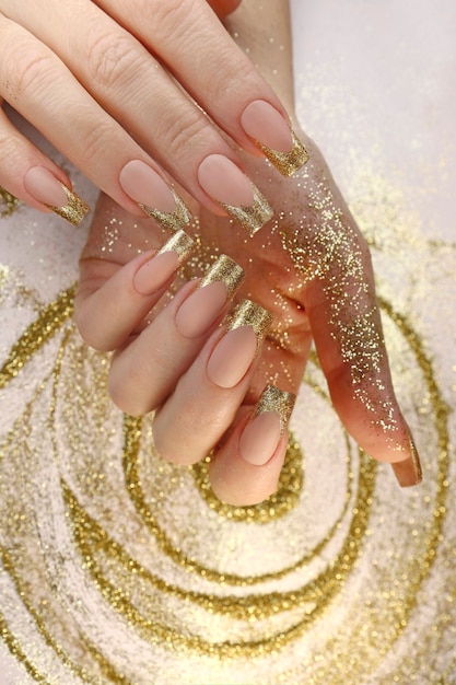 Goldene Mode French Manicure auf langen Nägeln mit Goldglitter.