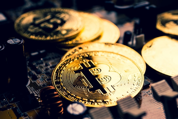 Goldene Münzen mit Bitcoin-Symbol auf einem Mainboard.
