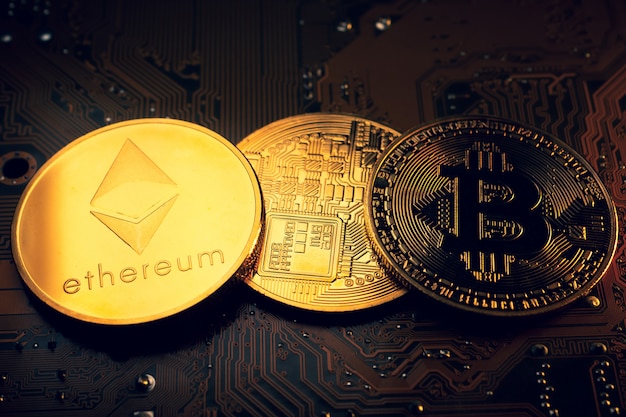 Goldene Münzen mit Ethereum und Bitcoin-Symbol auf einem Mainboard.