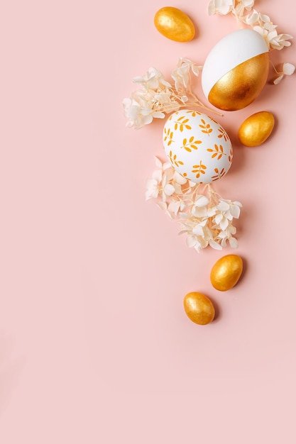 Foto goldene ostereier und weiße blumen auf pastellrosa hintergrund urlaubskonzept fröhliche osterkarte mit kopierbereich