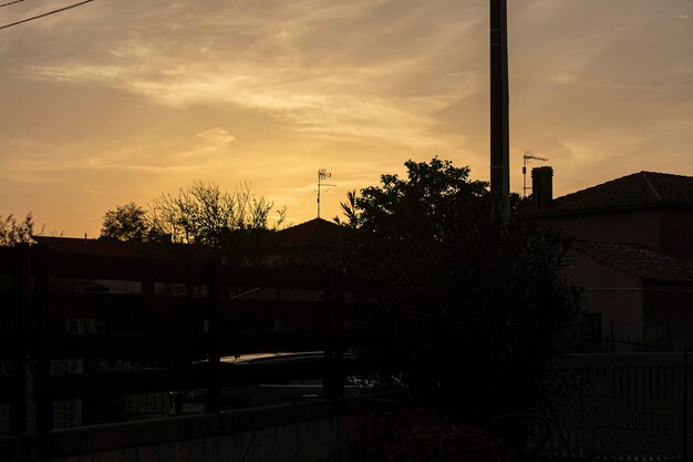 Goldene Schattierungen des Sonnenuntergangs filtern durch die Silhouette der städtischen Häuser und erzeugen eine ruhige Atmosphäre