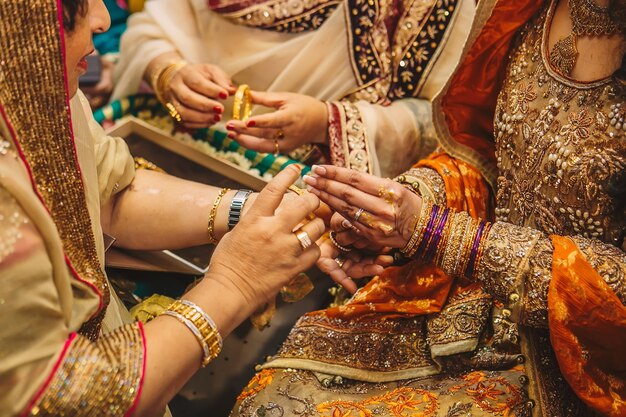 goldene Schmuckarmbänder und Ringe in Frauenhänden mit Henna