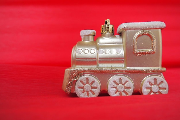 Goldene Spielzeugeisenbahnlokomotive auf einem roten und rosa Hintergrund mit Farbverlauf Neujahrs- oder Weihnachtskarte Eiszapfen und Schnee in einem Zug Freier Platz für Text Kopierbereich Festlicher Hintergrund