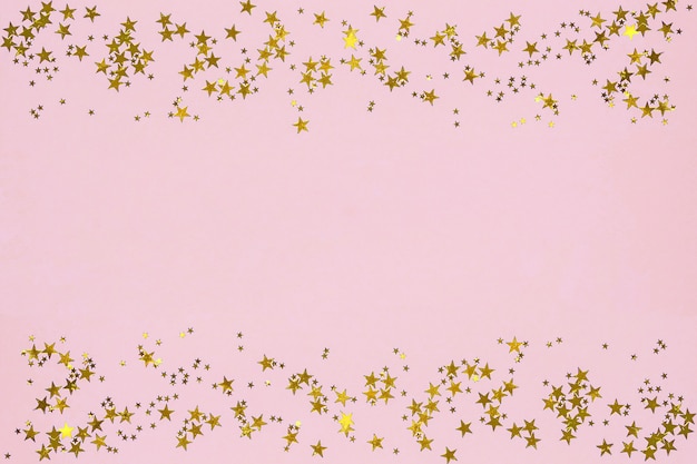 Goldene sternförmige Scheine auf rosa Hintergrund