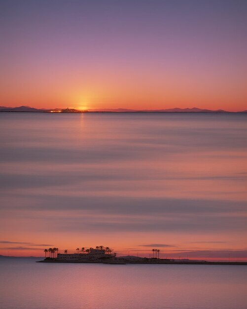 Goldene Stunde, rosa-orangefarbenes und violettes Licht, Sonnenuntergang über dem Mar Menor, Speire-Beugungen auf dem Wasser