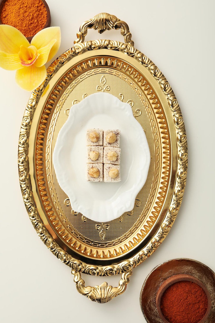 Goldene Tablettblume und Schüssel der orientalischen Süßigkeiten mit Gewürzen auf Draufsicht des weißen Hintergrundes