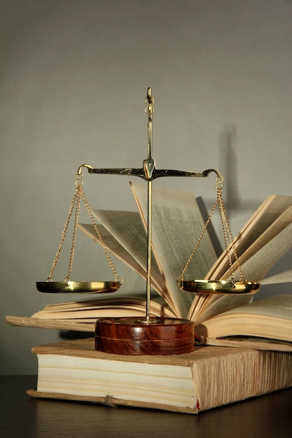 Goldene Waage der Gerechtigkeit und Bücher auf grauem Hintergrund