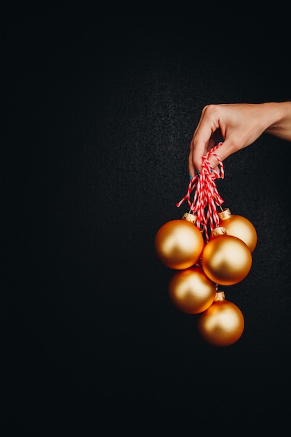 Goldene Weihnachtsbälle in der Hand der Frau lokalisiert auf schwarzem Hintergrund