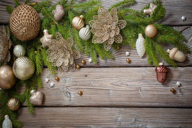 Goldene Weihnachtsspielzeuge mit Tannenzweigen auf dunklem Holzhintergrund