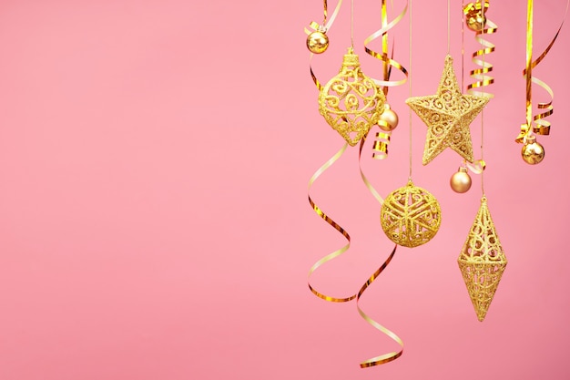 Goldene Weihnachtsverzierungen lokalisiert auf rosa