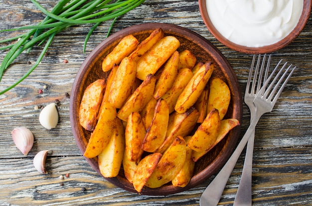 Goldene würzige Kartoffelschnitze gebraten oder im Ofen mit Knoblauch, Sauce und Zwiebel gebacken.