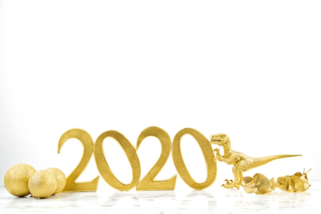 Foto goldene zahlen 2020 und spielzeugdinosaurier über dem weißen hintergrund. neujahrsfeier idee