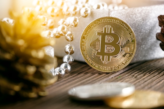 Goldener bitcoin gesetzt nahe Geschenkbox und Kiefernkegel