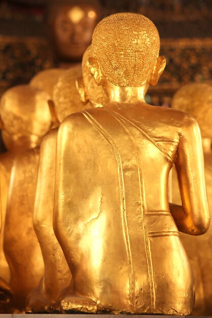 Goldener Buddha, der zurück sitzt.