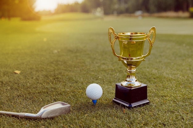 Foto goldener gewinner mit golfball und golfschläger auf grünem gras auf dem golfplatz