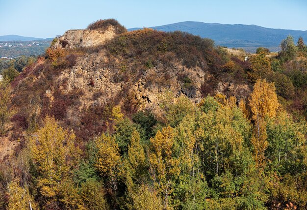 Goldener Herbst mit bunten Bäumen im alten Steinbruch. Felsen und gelbe Bäume