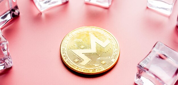 Goldener Monero XRM auf hellrosa Hintergrund Nahaufnahme Makroaufnahme Kryptowährung
