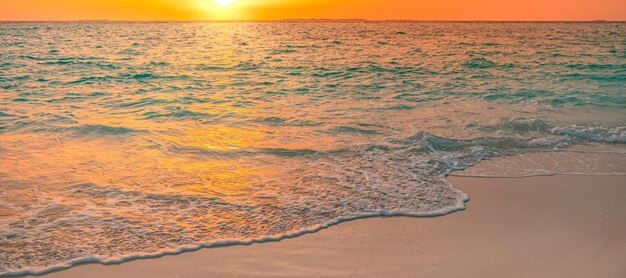 Goldener Wolkenhimmel, Reflexion der Sonne im Wasser und Sand am Strand. Konzept des romantischen Urlaubs