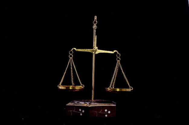 Goldenes Balance-Gewicht mit zwei Pfannen auf einem schwarzen Bacground