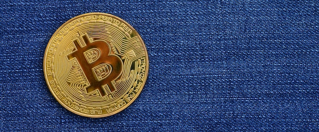 Goldenes Bitcoin liegt auf einem Jeansstoff. Neues virtuelles Geld. Neue Kryptowährung in Form der Münzen