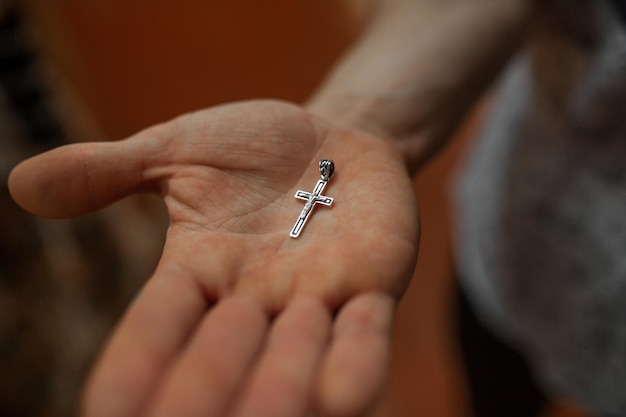 Goldenes Brustkreuz auf der Handfläche Religionsgoldschmuck des Konzepts