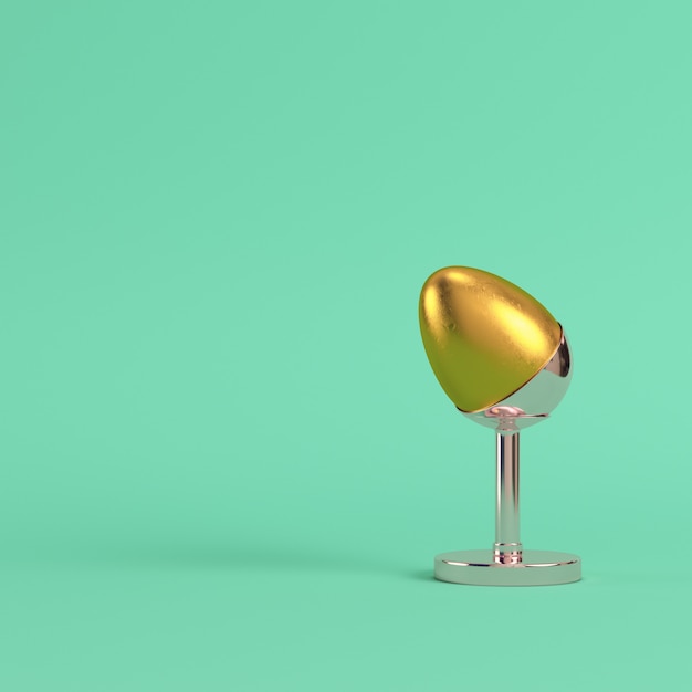 Goldenes Ei mit Silberstand auf hellgrünem Hintergrund