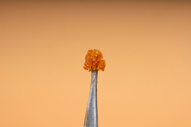 Goldenes Pho-Cannabis-Crumble-Harz mit frischen Terpenen mit hohem THC-Gehalt auf beigem Hintergrund