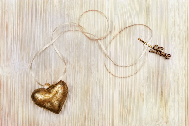 Goldfarbenes Herz mit weißem Band auf Retro-Holz