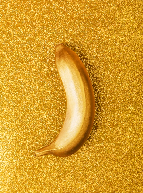 Goldfarblebensmittel, goldene Banane auf hellem Funkeln oder Schimmerhintergrund