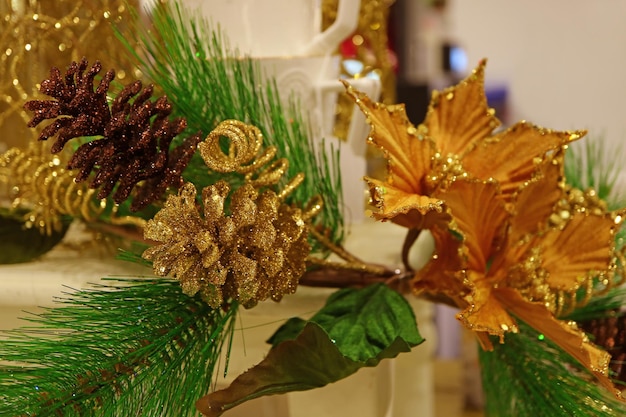 Goldglitzernde trockene Tannenzapfen und künstliche Blumen auf Tannenblättern für die Weihnachtsdekoration